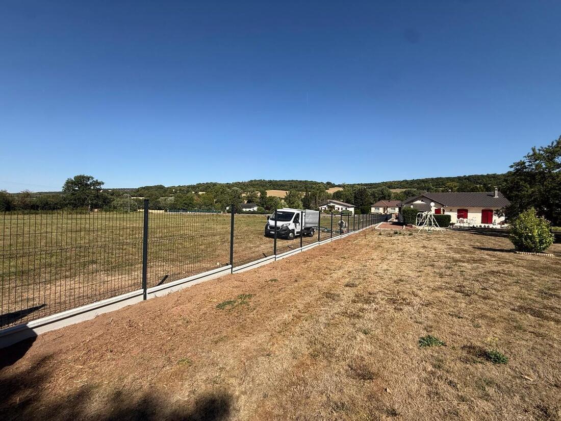 Panneaux de clôture rigide posés sur soubassement béton le long d'une allée pavée