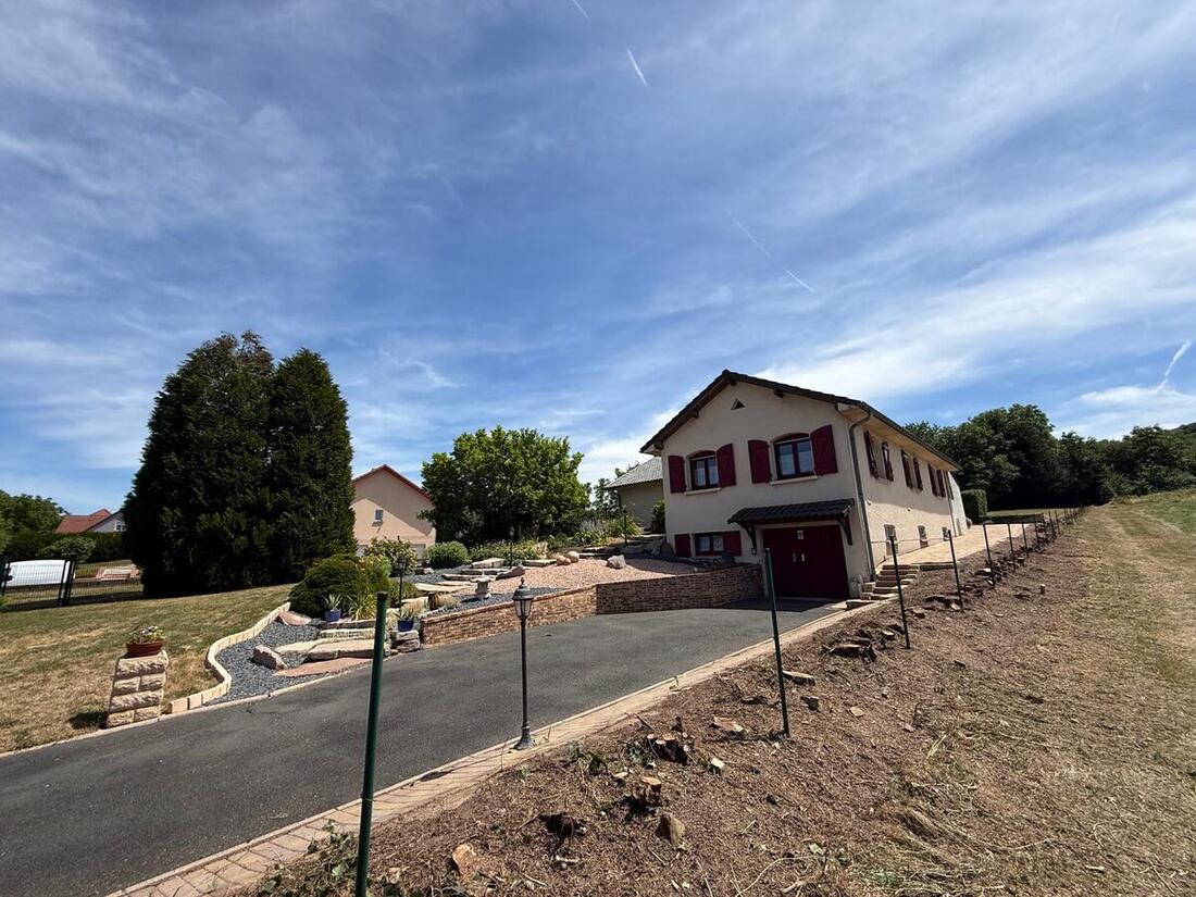 Terrain en pente sans clôture avant intervention à Saint-Avold, piquets de tracé plantés le long de l'allée