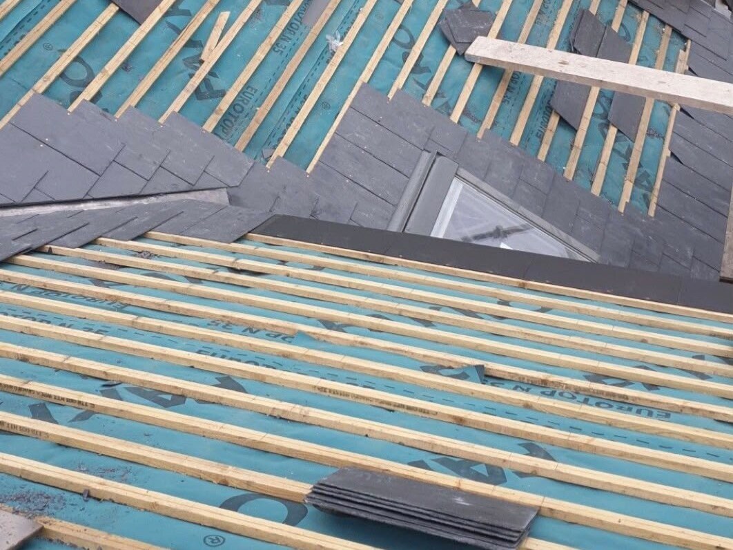Chantier de couverture en cours, pose d'ardoises sur liteaux