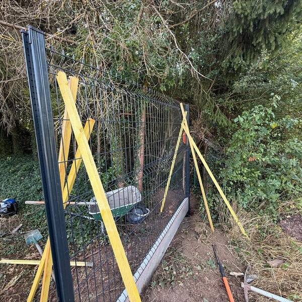 Panneaux de clôture rigide maintenus par des étais pendant la prise du béton