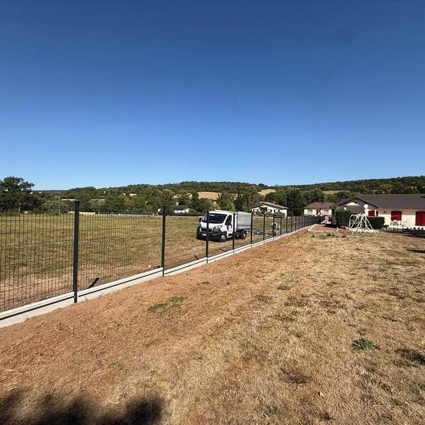Panneaux de clôture rigide posés sur soubassement béton le long d’une allée pavée
