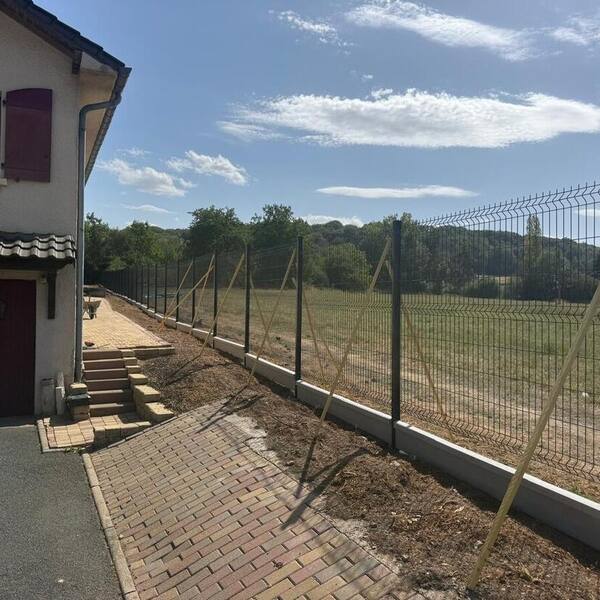 Chantier de clôture rigide en cours le long d’une allée pavée