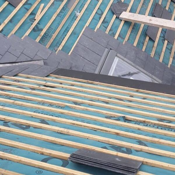 Chantier de réfection de couverture en cours, liteaux apparents et pose d’ardoises